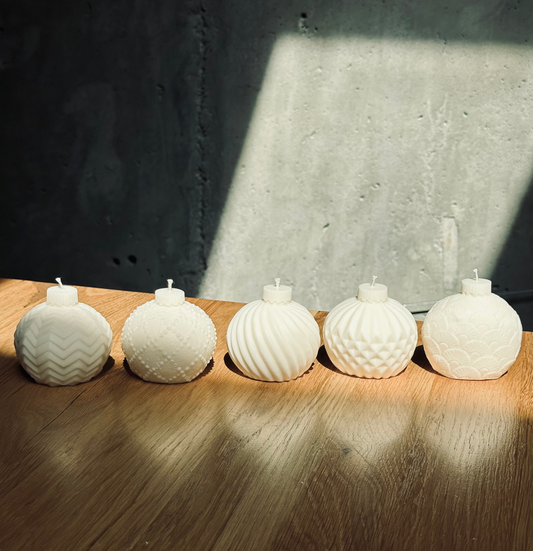 Five white textured candles on a wooden surface with a dark background