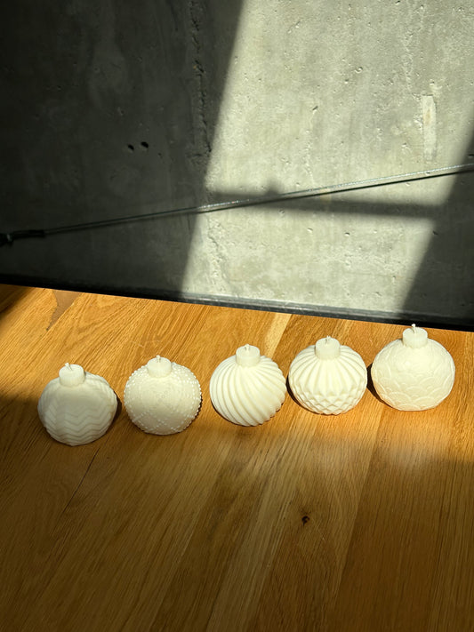 Five white soy candles items arranged on a wooden surface with a concrete wall in the background.