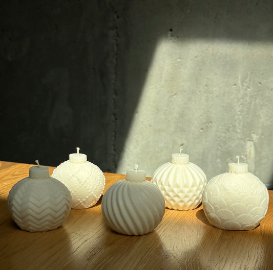 Set of white textured candles on a wooden surface with a concrete wall background