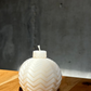 White candle with a zigzag pattern on a wooden surface against a dark background