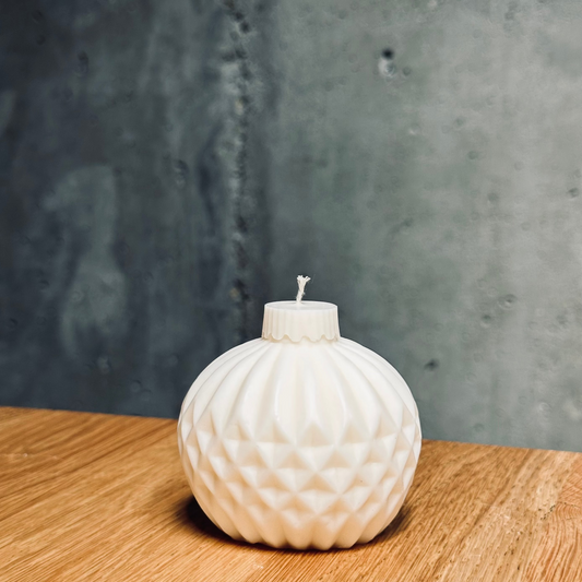 White textured candle on a wooden surface with a gray concrete wall background