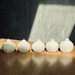 Five white textured candles on a wooden surface with a dark background