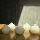 Set of white textured candles on a wooden surface with a concrete wall background